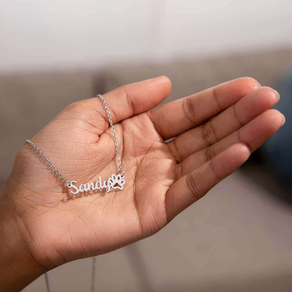 Personalized More Than Charms Name Necklace with paw print charm in hand.