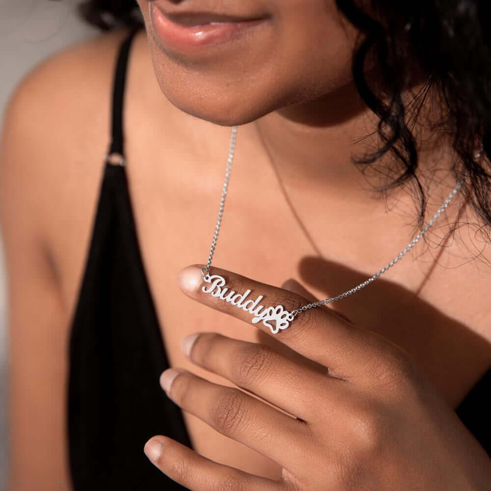 Woman wearing More Than Charms Name Paw Necklace, personalized with "Buddy" and paw print design, showcasing a thoughtful pet lover gift.